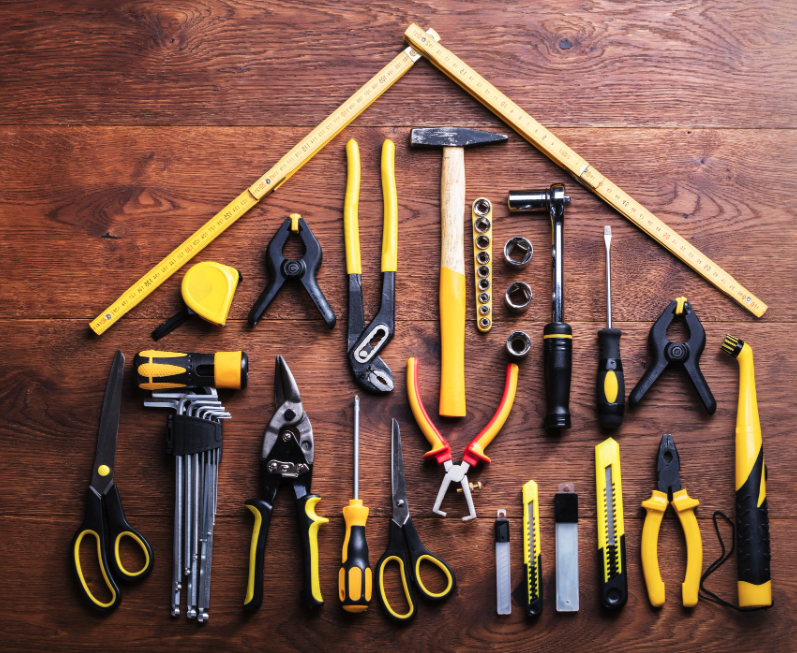 A toolbox arranged in the shape of a house on a wooden table